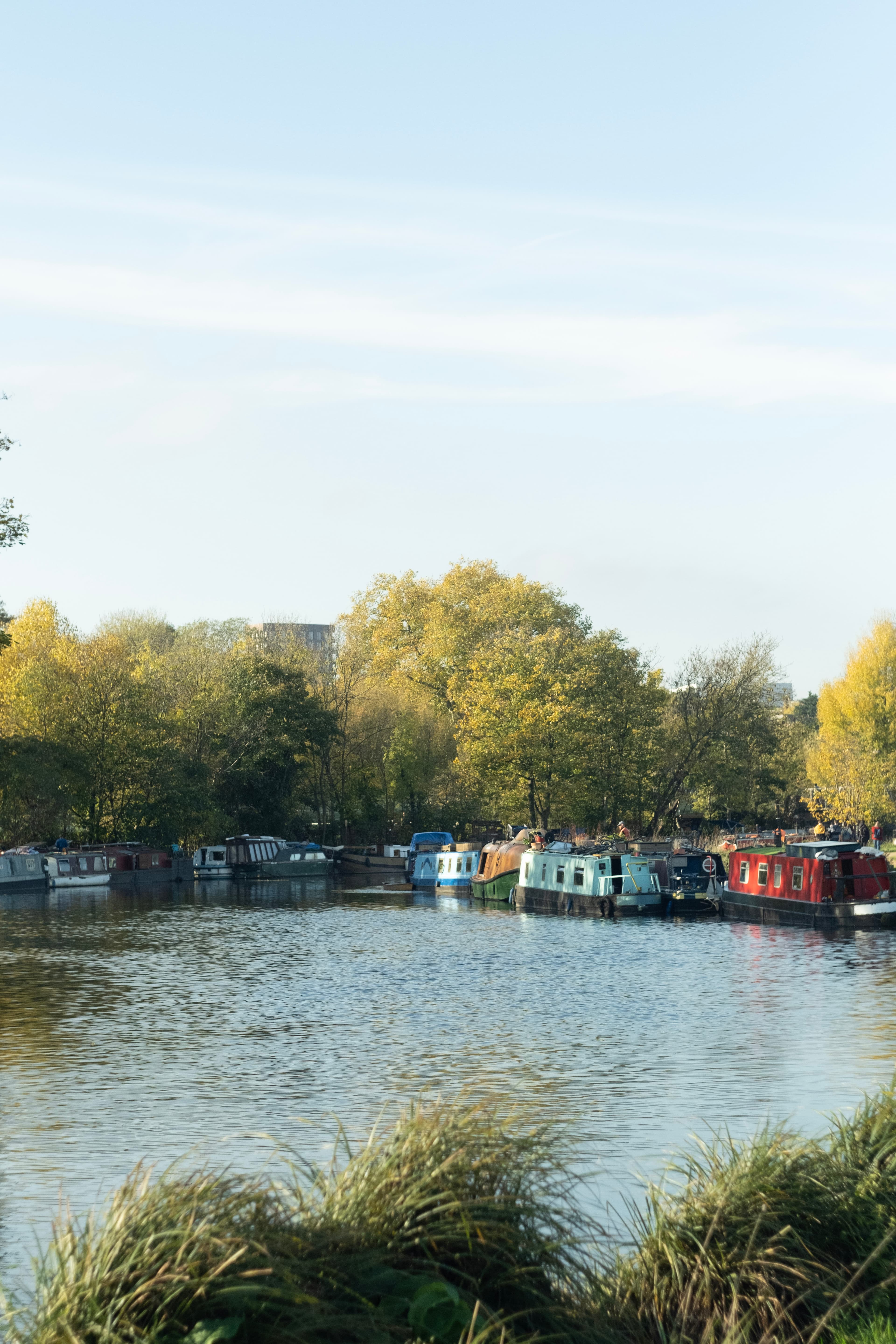 A row of narrowboats moored along a canal at sunset